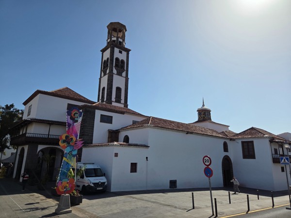 Facade and bell tower of Iglesia de la Concepción in Santa Cruz de Tenerife under a bright sky.