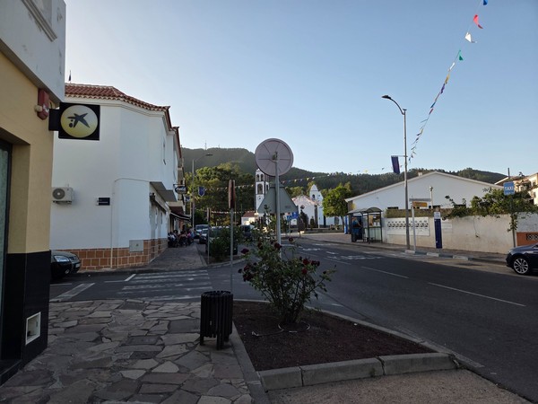Central street in Santiago del Teide with a bus stop, taxi stand and the church tower visible in the background.