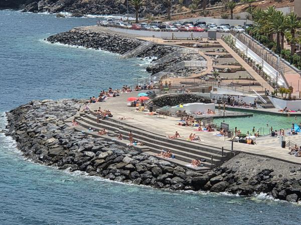 People sunbathing on concrete platforms by the sea