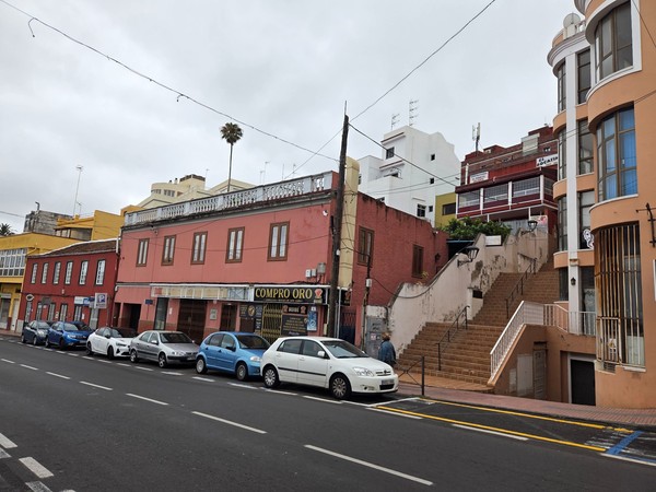 Row of colorful buildings with a ‘Compro Oro’ shop and exterior stairways on a Tacoronte street.