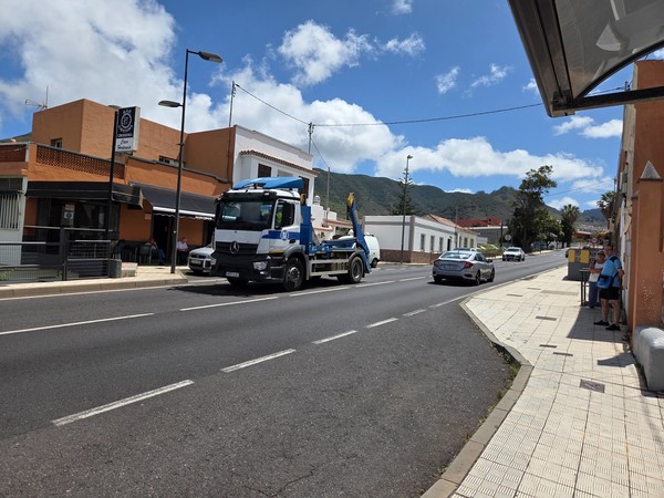 View from a bus stop on the TF-13 in Tejina with passing vehicles and people waiting.