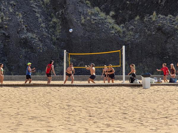 Energetic volleyball players dive and serve on the courts located at the far end of the beach, a spot for sports lovers.