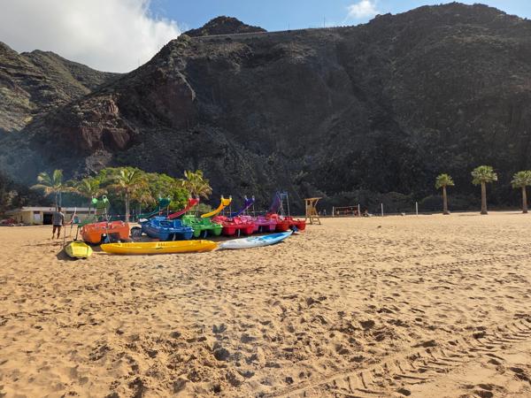 Colorful pedal boats and kayaks line up for rent, adding a splash of brightness and inviting visitors to explore offshore.